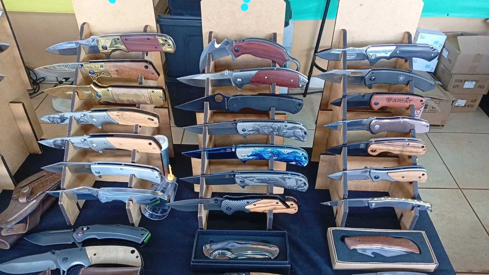 Diversos canivetes com cabos de madeira e lâminas trabalhadas expostos em suportes