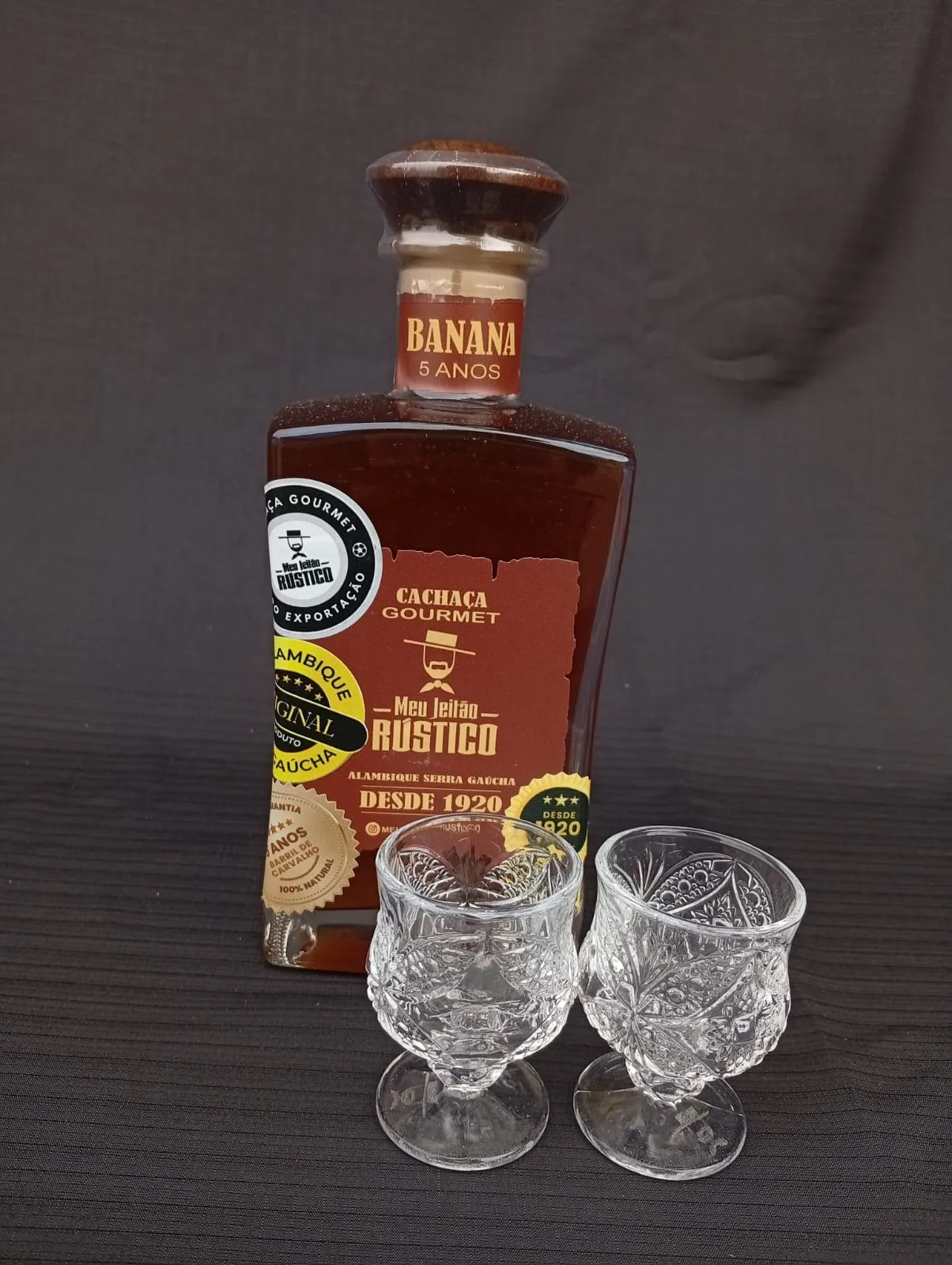 Kit com garrafa de cachaça premium sabor banana de 750 ml e dois copos de vidro