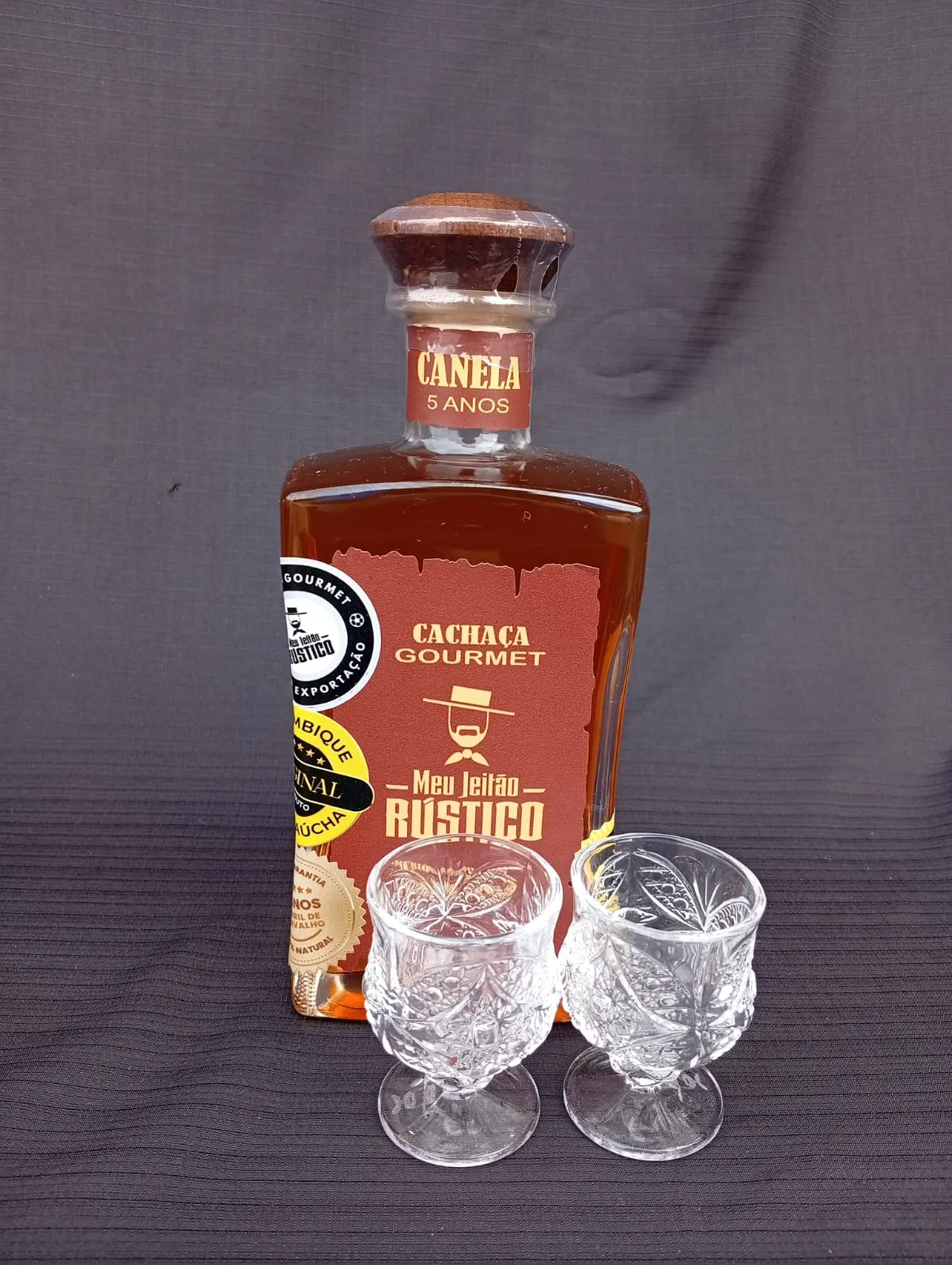 Kit com garrafa de cachaça premium sabor canela de 750 ml e dois copos de vidro